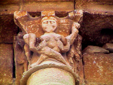 Capitel con figura de mujer desnuda, cuyos pechos son succionados por dos serpientes a las que ella sujeta con sus manos.